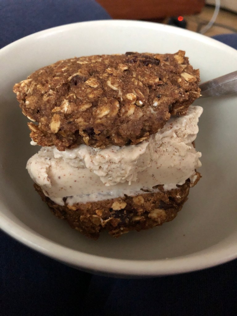 ice cream sandwiched between oatmeal raisin cookies in a plain tan bowl