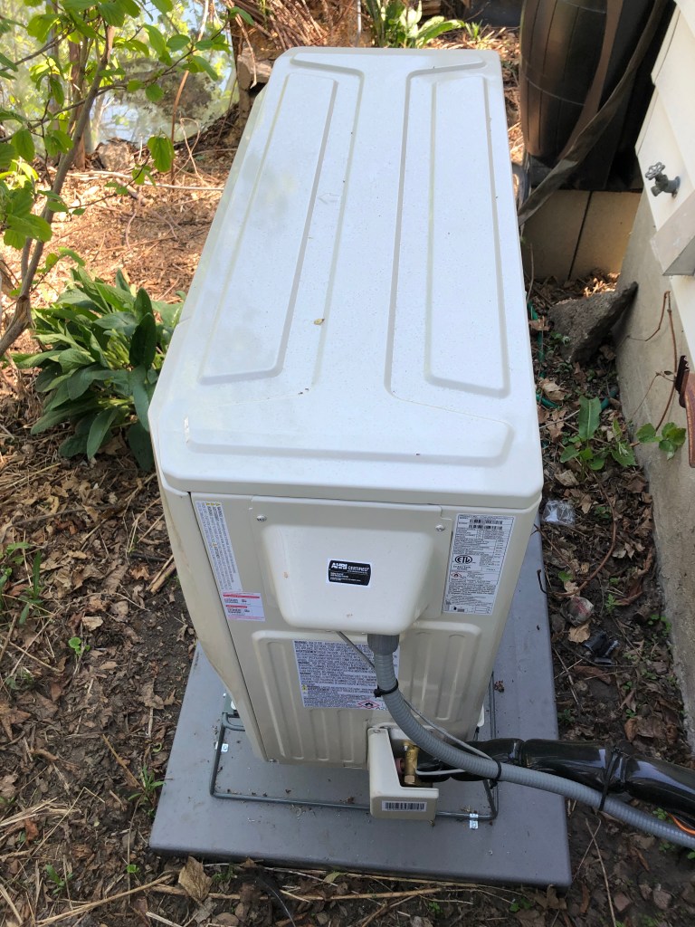 heat pump sitting outside house on a platform