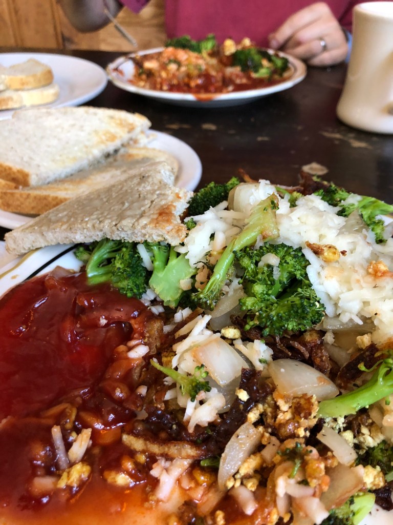 super green earth breakfast plate tofu broccoli onion vegan cheese hash brown potatoes and toast with some ketchup on the side
