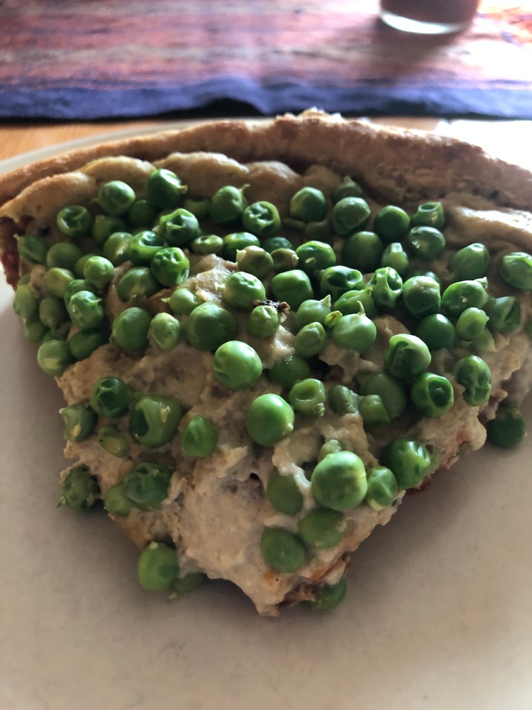 a slice of pizza with green peas on top