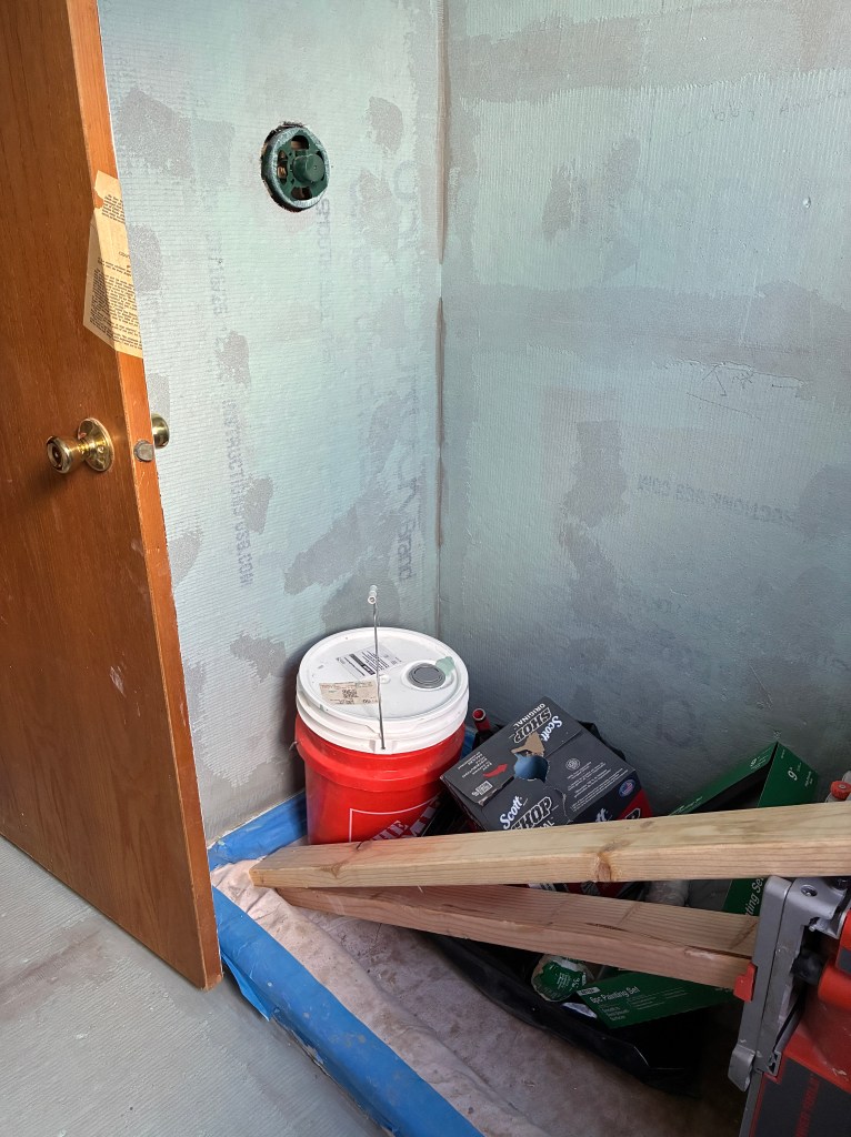 bathroom shower with bare sheetrock walls and building supplies