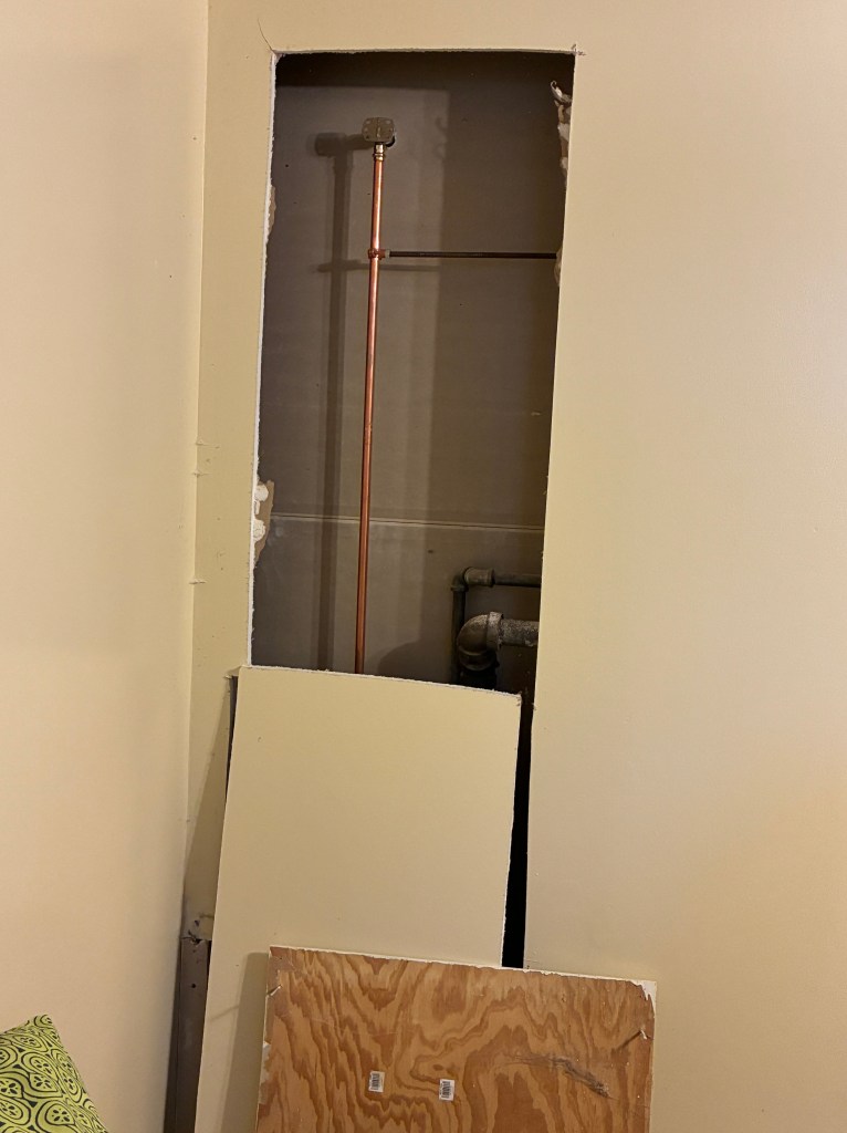hole cut in wall to expose bathroom plumbing