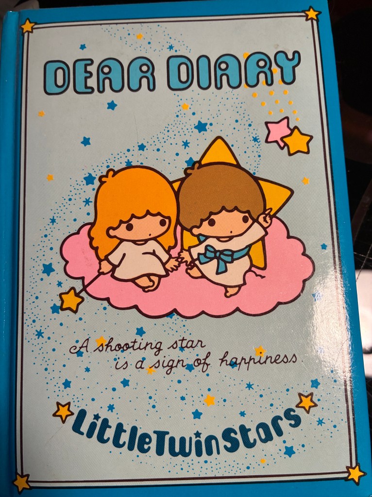 Diary cover has two cartoon children sitting on a pink cloud and says Little Twin Stars